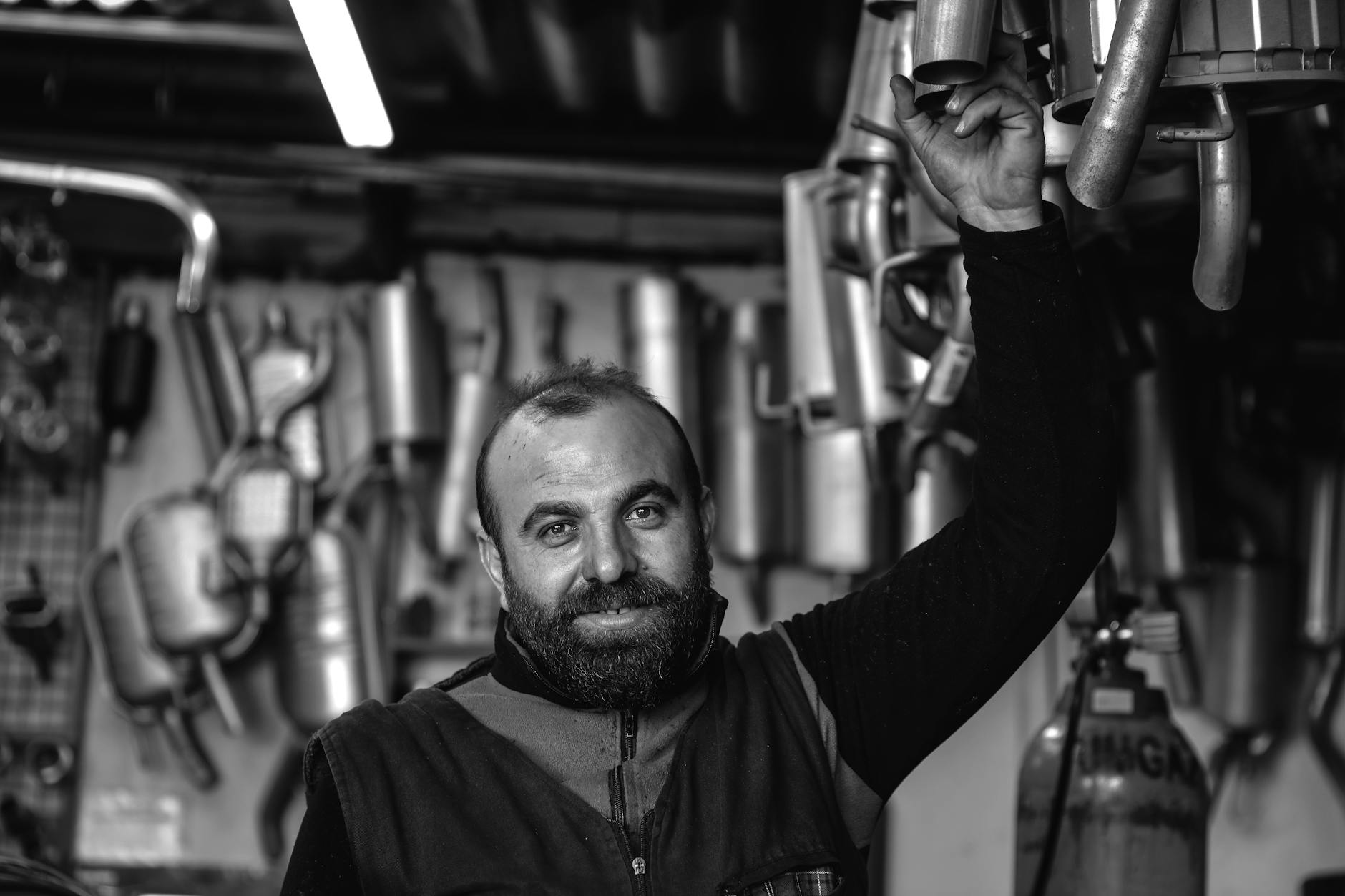 Uśmiechnięty mechanik w warsztacie trzyma nowy tłumik samochodowy