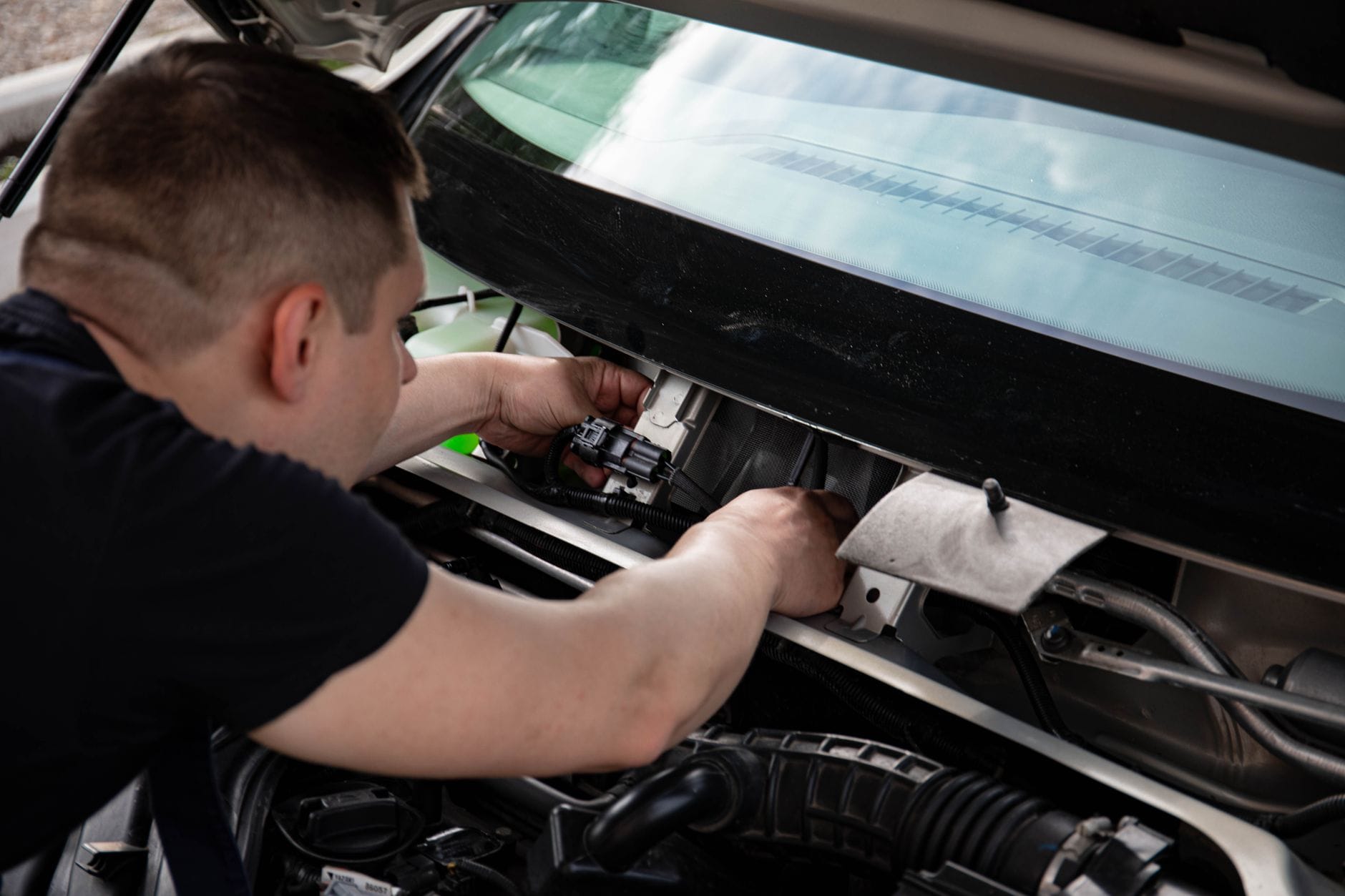 Mechanik sprawdza instalację elektryczną w komorze silnika auta