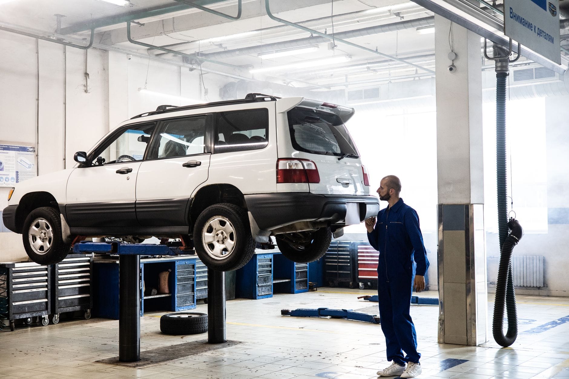 Mechanik sprawdza podnieste rodzinne SUV w nowoczesnym warsztacie