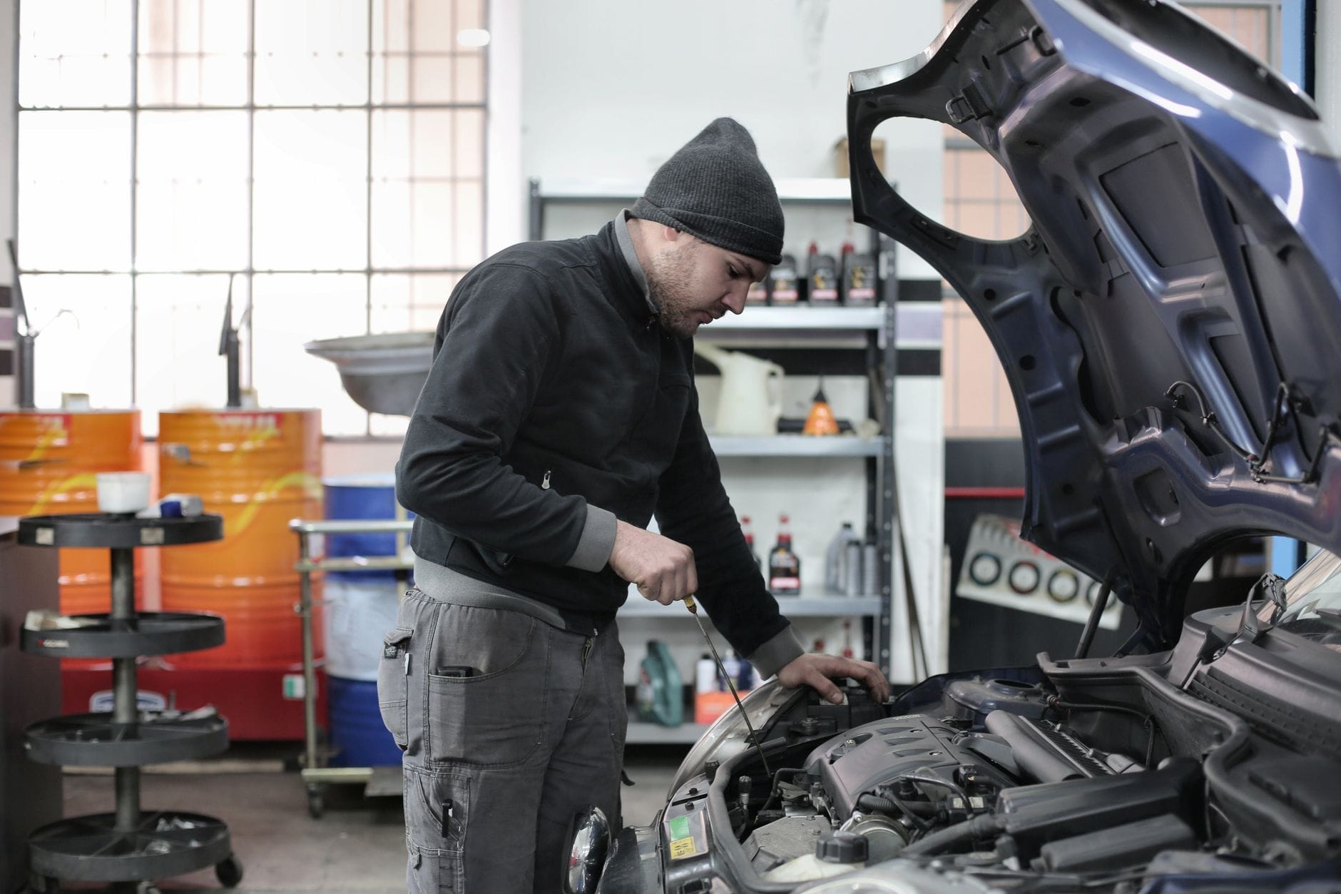 Mechanik sprawdzający pracujący silnik samochodu w warsztacie
