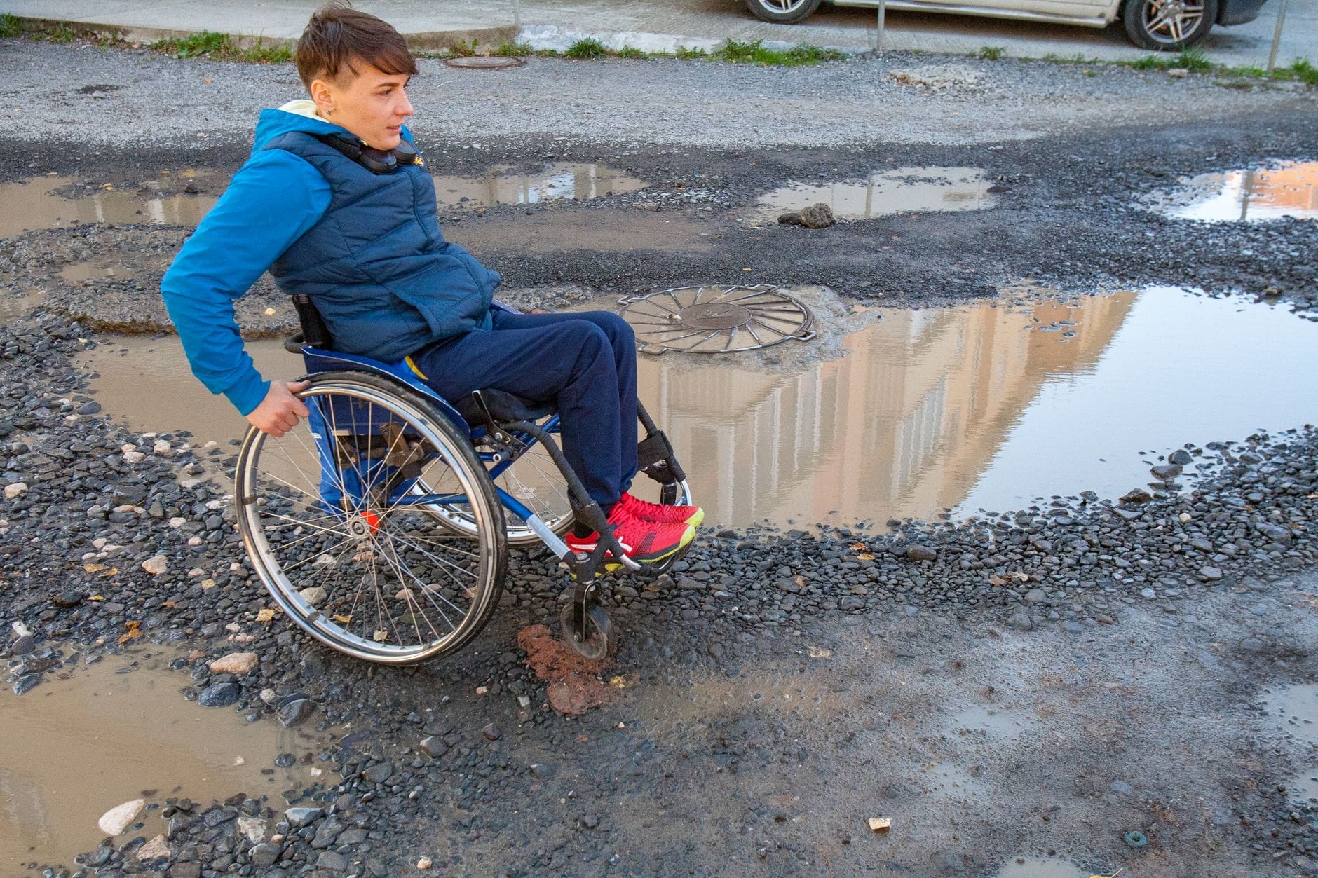 Mężczyzna na wózku inwalidzkim pokonuje nierówną miejską ulicę