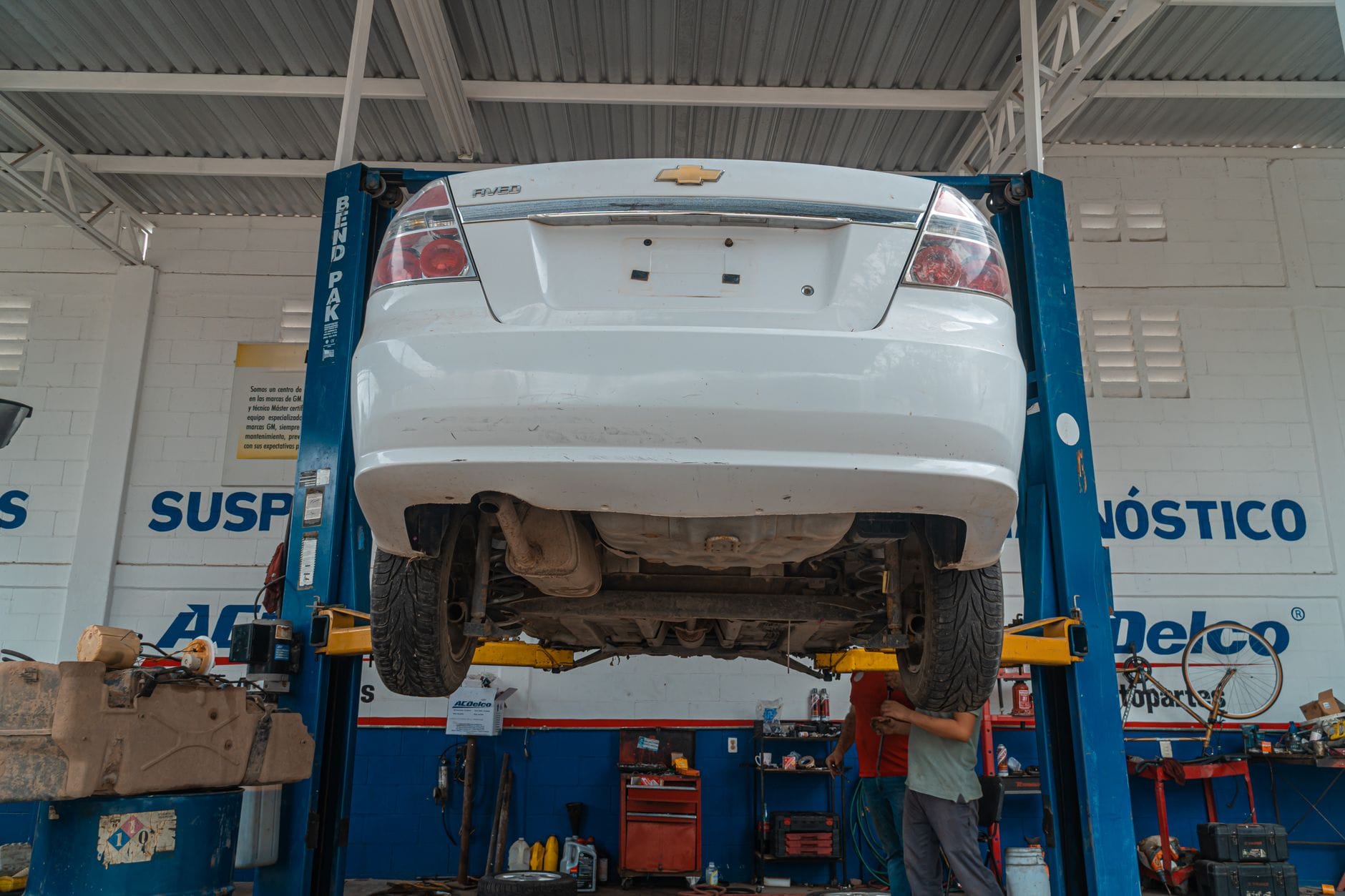 Biały Chevrolet uniesiony na podnośniku w warsztacie samochodowym